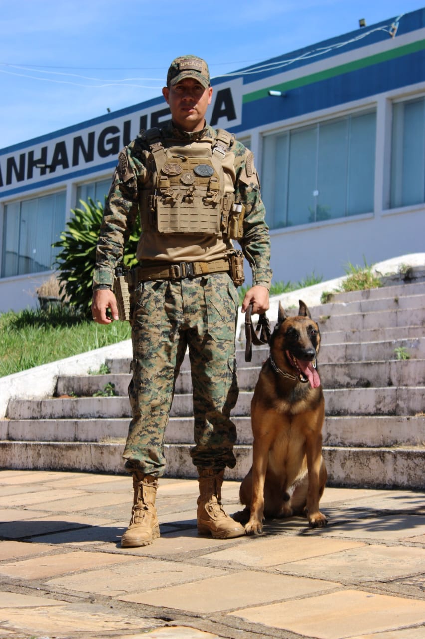 Retrato de corpo inteiro de Guilherme fardado com um malinois